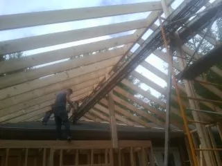 Rafters going up over a new addition with a worker on the wall in Marlborough